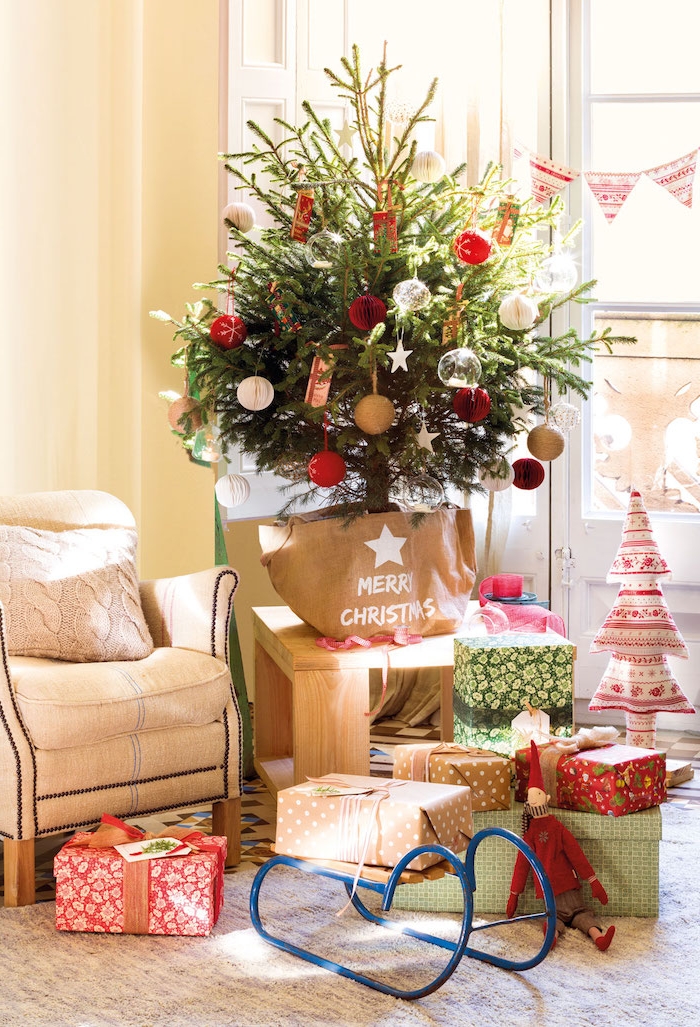 Kleiner Weihnachtsbaum in Geschenktüte, rote und weiße Christbaumkugeln, bunt verpackte Weihnachtsgeschenke 