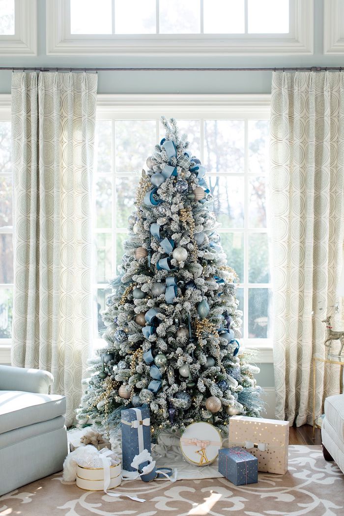 Künstlicher Weihnachtsbaum geschmückt mit weißen und hellblauen Christbaumkugeln und künstlichem Schnee 