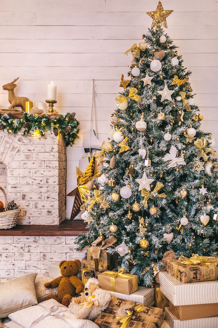 Weihnachtsbaum mit viel Schmuck, weiße Christbaumkugeln, goldene Schleifen, viele Weihnachtsgeschenke unter dem Baum 
