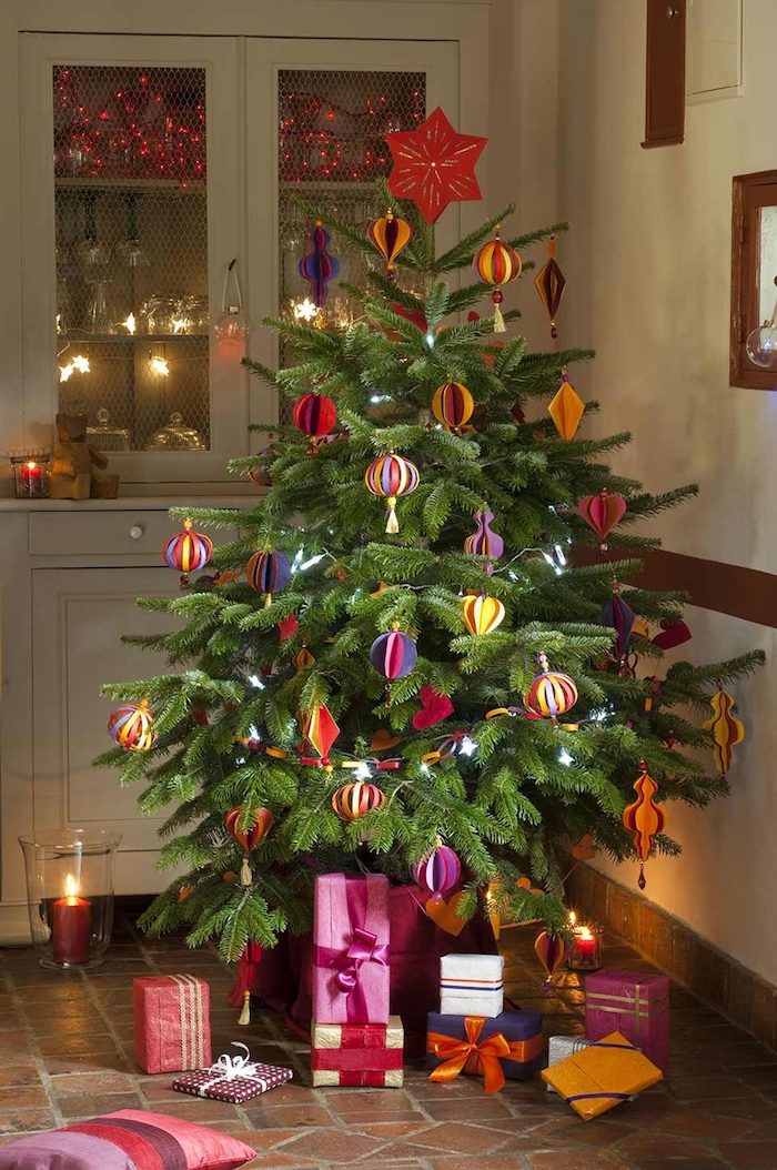 Weihnachtsbaum schmücken mit Christbaumkugeln aus Papier, Weihnachtsgeschenke verpackt mit buntem Geschenkpapier 