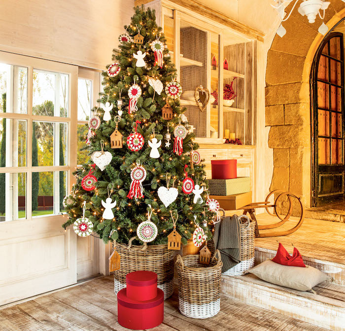 Echter Weihnachtsbaum geschmückt mit bunten Aufhängern in Form von Häuschen, Herzen und Engeln 