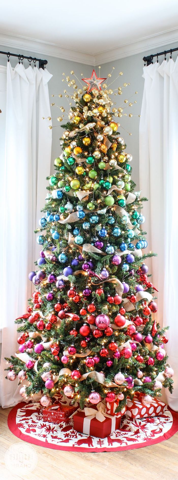 Tannenbaum mit bunten Christbaumkugeln in Schichten schmücken, Dekoband zwischen den Weihnachtskugeln, Geschenke unter dem Baum 