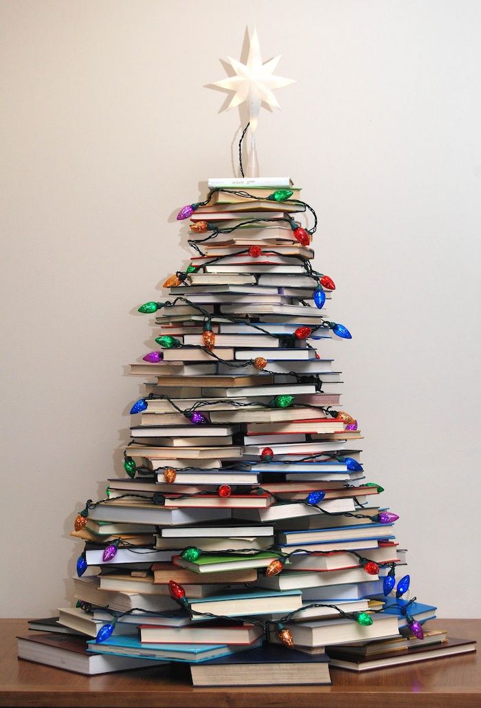 Weihnachtsbaum aus Büchern, geschmückt mit Lichterkette und Christbaumspitze, coole Alternative zum klassischen Tannenbaum