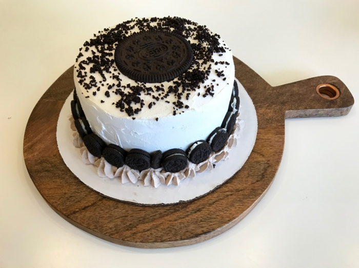 Torte mit weißer Creme, ein großer Keks in der Mitte, Mini Oreos an den Seiten, Oreo Cake