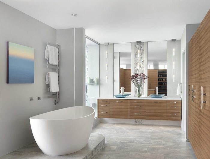 graue wände und eine kleine weiße freistehende badewanne und ein badezimmer spiegelschrank aus holz