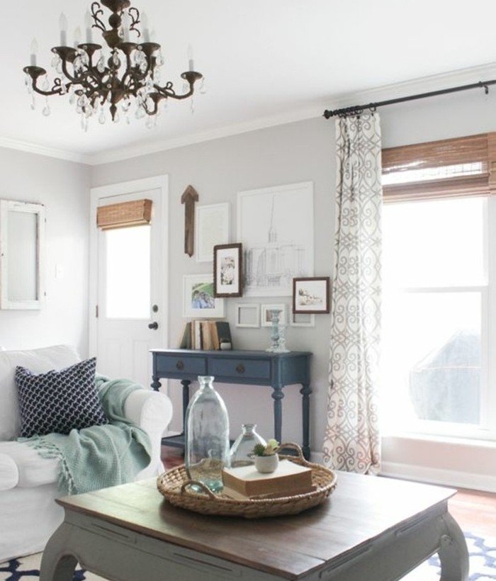 Wohnzimmer Grau Weiß, ein Kronleuchter, weiße Wände, weißes Sofa, ein grauer Tisch, bunte Gardinen