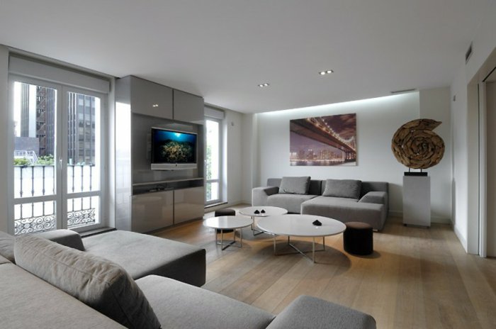 Wohnzimmer Weiß Grau, zwei graue Sofas, drei runde Tische, Laminat Boden, ein Skulptur