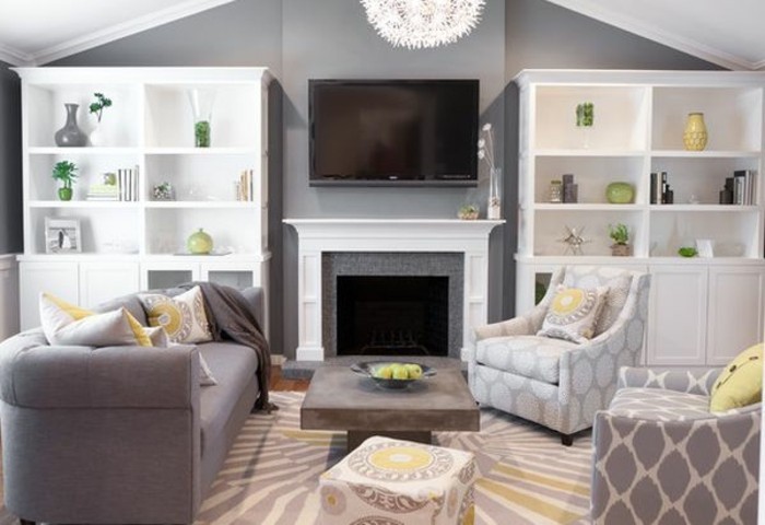 graue Wohnzummermöbel mit geometrischen Motiven, ein bunter Teppich, weiße Regale