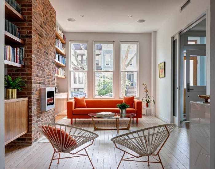 orangenfarbiges sofa, wohnzimmer ideen modern, ziegelwand mit kamin, geflochtene stühle