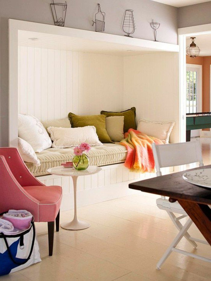 ein Sofa in der Wand eingebaut, rosa Sessel und kleiner Tisch, eine Leseecke, kleines Wohnzimmer einrichten