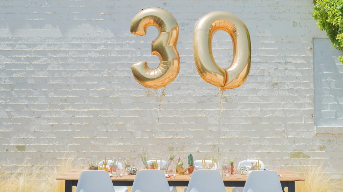 zwei Ballons mit den Ziffern drei und null, eine Ziegelmauer, Tischdeko mit Kakteen, Geburtstagsdeko für dreißigsten Geburtstag 