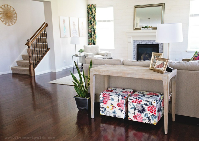 braune glänzende Diele, ein Kamin und ein Spiegel, ein Tisch aus Holz, bunte Hocker, Wandgestaltung für Wohnzimmer