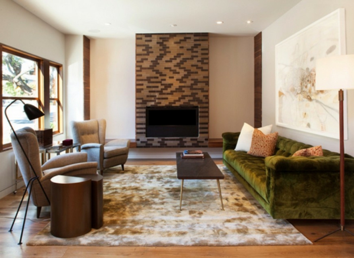 ein grünes Sofa, ein brauner Teppich, zwei braune Sessel, eine Fernsehwand mit Backstein Optik, Wanddeko Wohnzimmer