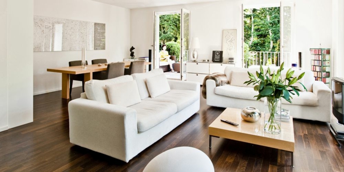 zwei weiße Sofas, Laminat Boden, ein kleiner quadrate Tisch, eine weiße Landkarte, Wohnzimmerwand