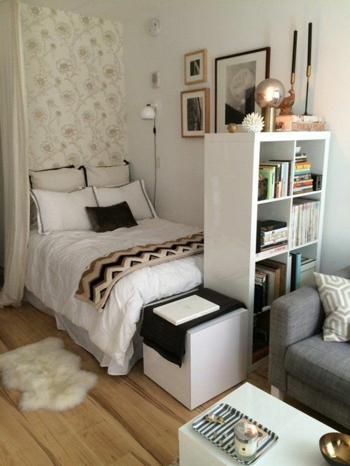 Wohnzimmer und Schlafzimmer in einem Raum, ein graues Sofa, weißer Tisch mit bunten Dekorationen