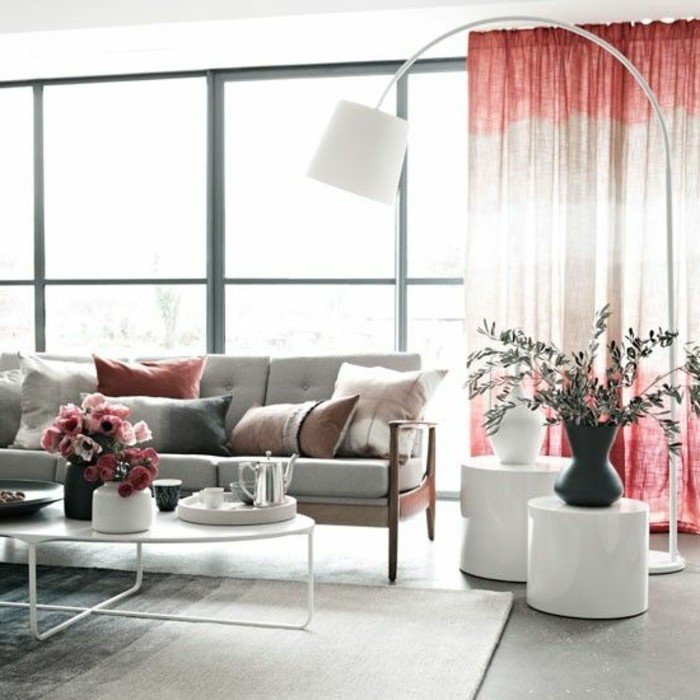 ein graues Sofa, bunte Kissen, ein Vorhang in zwei Farben, ein grauer Teppich, zwei Vasen, Einrichtungsideen Wohnzimmer