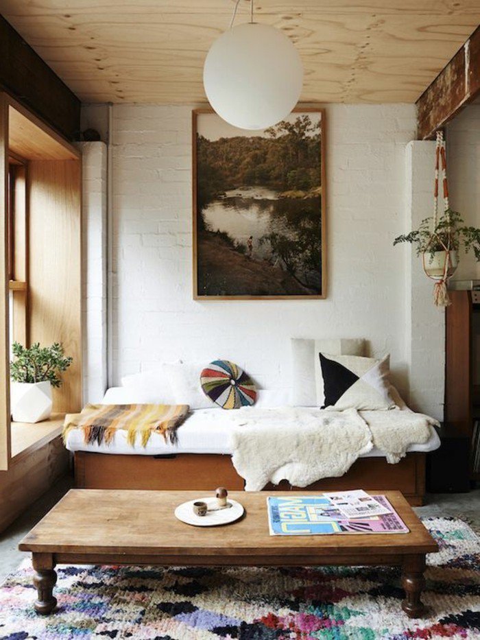 ein weißes Sofa, ein hölzerner Tisch, bunte Kissen, eine runde Lampe, ein bunter Teppich, Wohnzimmer gestalten