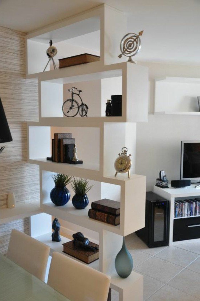 ein weißer Raumteiler mit Büchern und kleine Dekorationen, weiße Fliesen, kleine Räume einrichten