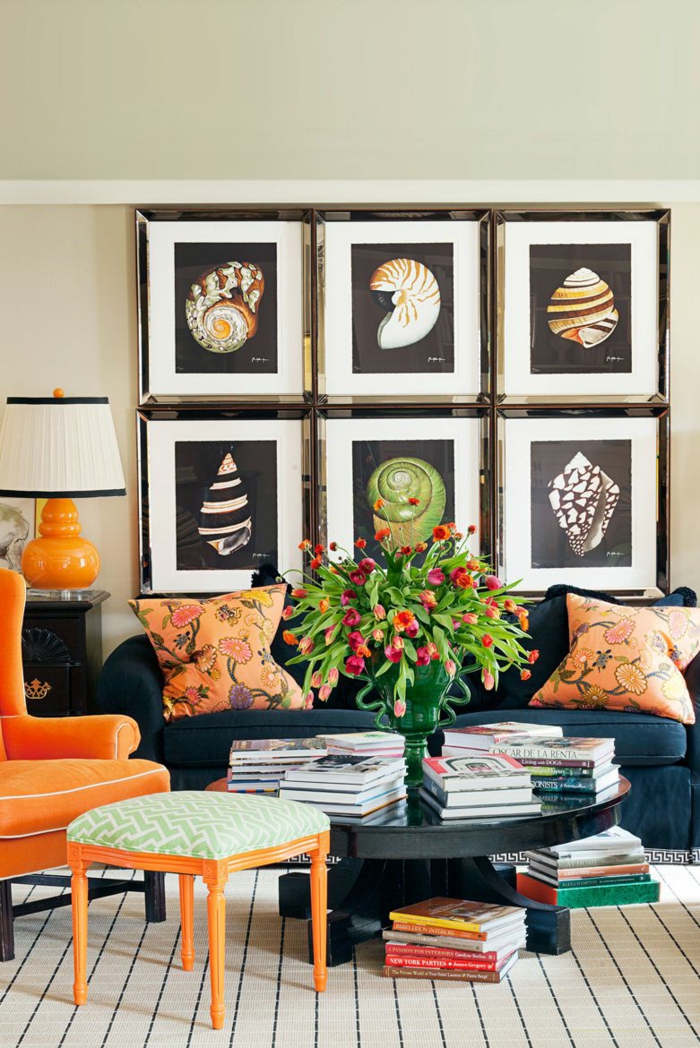 sechs Bilder, ein dunkelblaue Sofa, ein oranger Sessel, eine Vase mit Blumen, kleine Fliesen als Bodenbelag, Wohnzimmer Farben