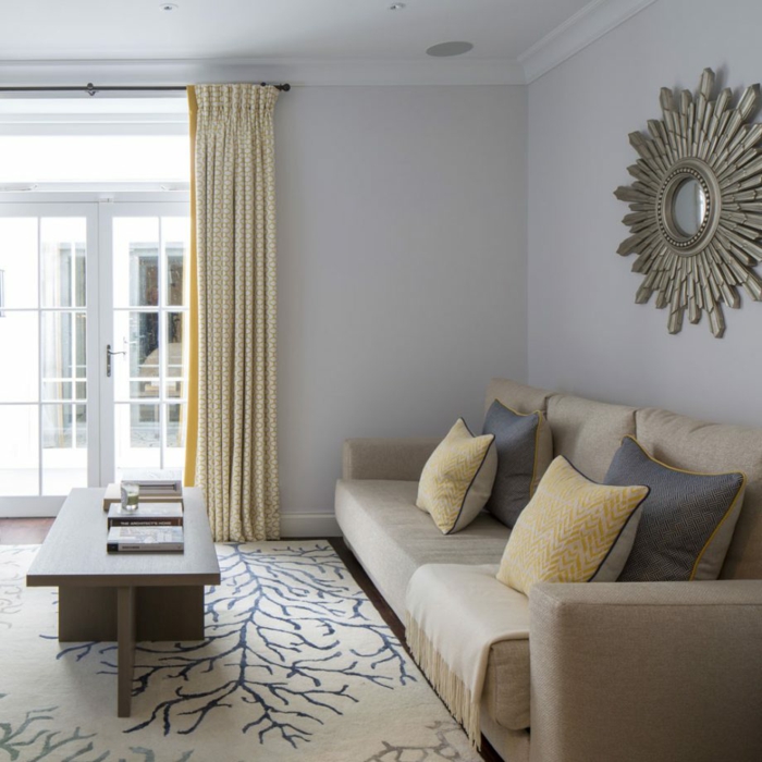 ein braunes Sofa, ein weißer Teppich mit schönen Motiven, gelbe und blaue Kissen, Wohnzimmer Farben