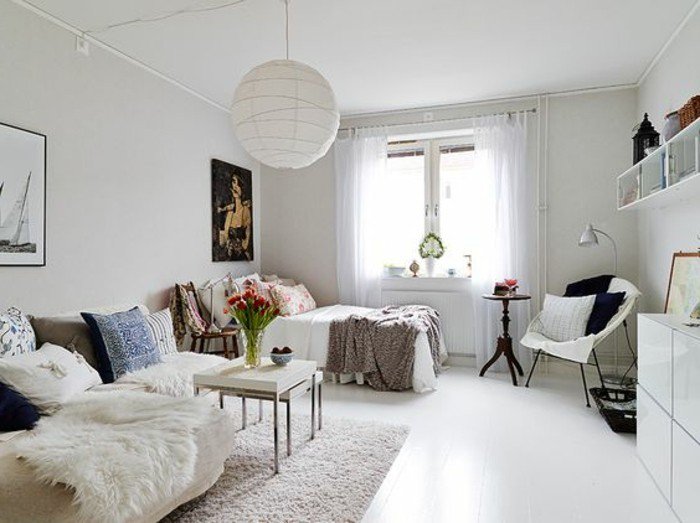 ein beiges Sofa mit weißen Decken, bunte Kissen, ein kleiner weißer Tisch, Wohnzimmer gestalten