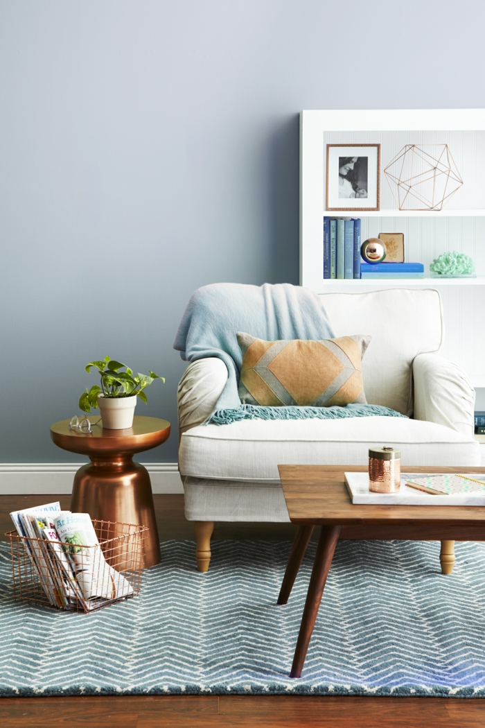 ein blauer Teppich, ein weißer Sessel, weiße Regale mit Dekorationen, ein runder Tisch, Wohnzimmer Ideen Wandgestaltung
