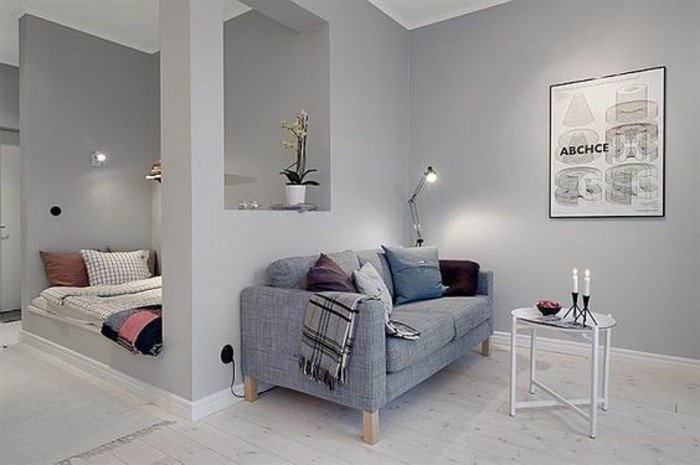 ein graues Sofa, bunte Kissen, ein schwarz-weißer Schal, ein runder weißer Tisch, kleine Räume einrichten