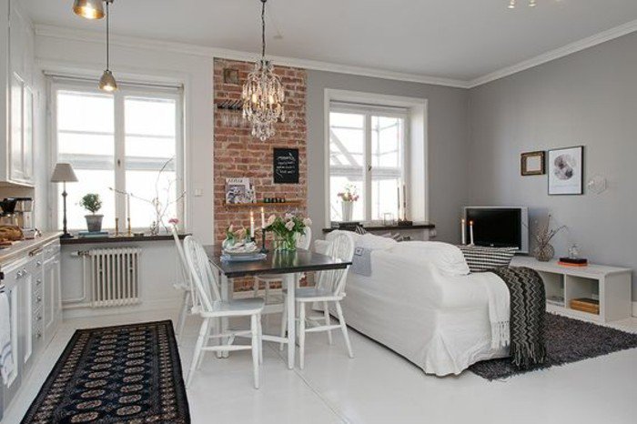 einraumwohnung, robuster look mit modernem interieur kombinieren, weißes sofa mit fernsehwand dagegen, küchenzeile, schwarzer teppich
