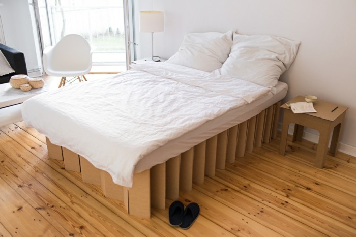 bett design idee, pappmöbel für erwachsene, ein doppelbett mit sessel daneben und pappiertischchen