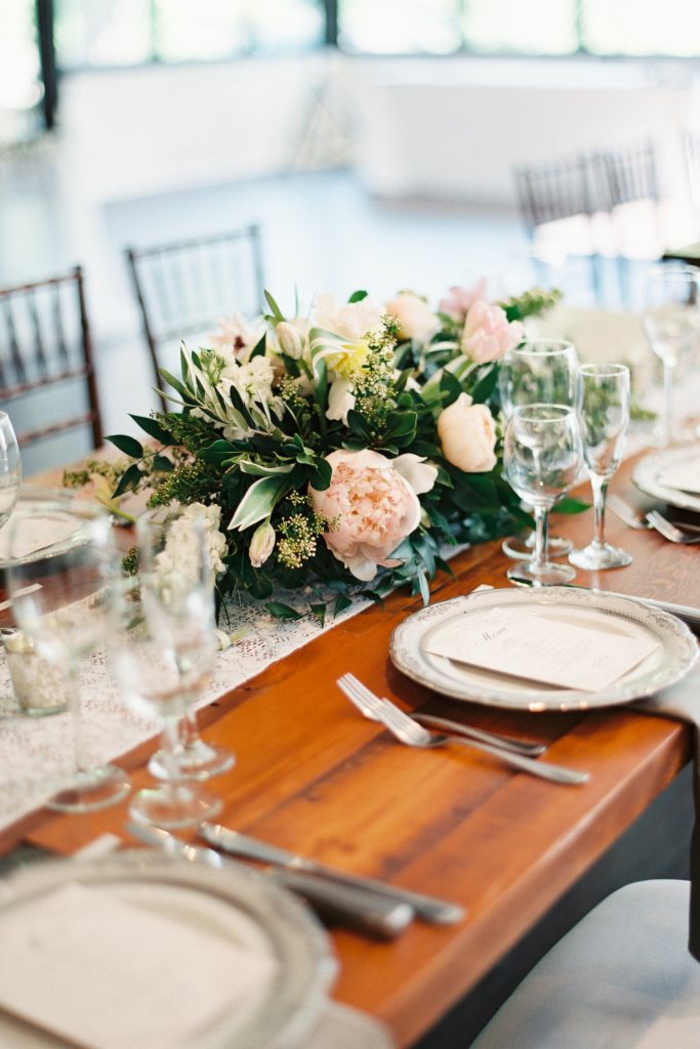 Blumen Tischdeko im Glas, rosa Blumen, goldfarbene Tischläufer, Tisch aus Holz, beige Teller