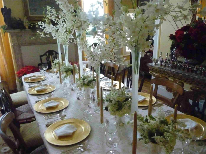 Blumen Tischdeko im Glas, viele hohe Vasen mit weißen Blumen, goldfarbene Teller, weiße Tischdecke