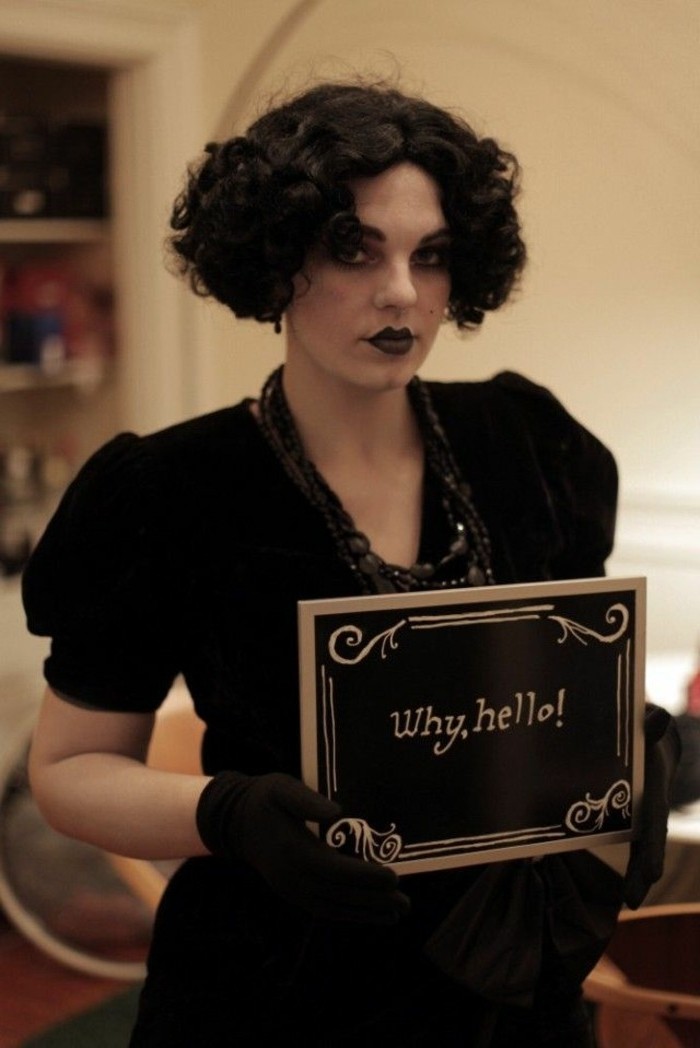 gruselige kostüme, eine theater schauspielerin in schwarzer verkleidung, kurze haare, kleid mit decollete und schwarze perlen