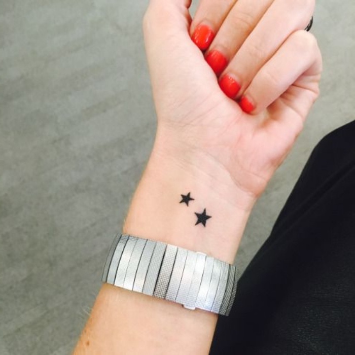 handgelenk tattoo zum inspirieren, zwei sterne, schwarze sternchen, rote nägel, nageldesign, große armband