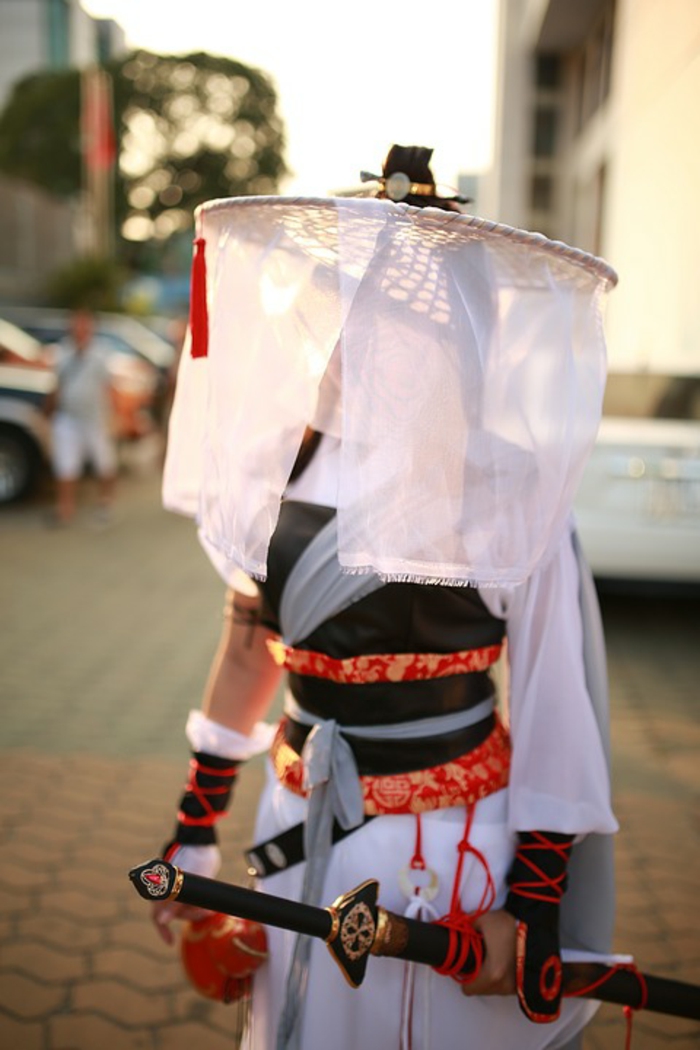 Ein Mädchen mit Kostüm und Katana Schwert, ein Samurai Ninja Kostüm in weißer Farbe