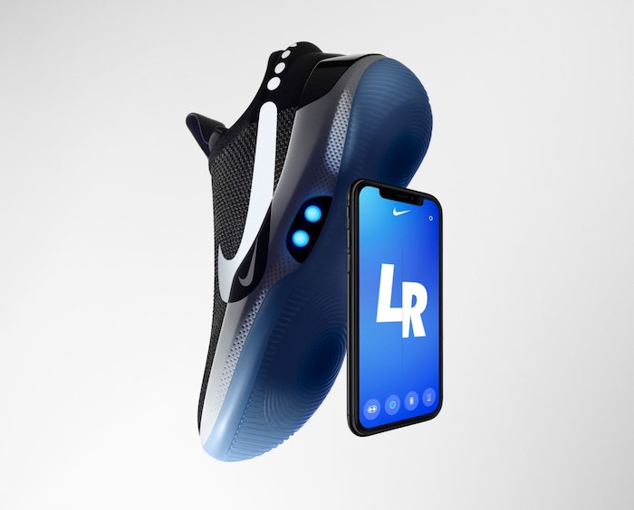 kleines schwarzes smartphone mit einem blauen display und ein schwarzer schuh nike-adapt-bb mit blauen sensoren