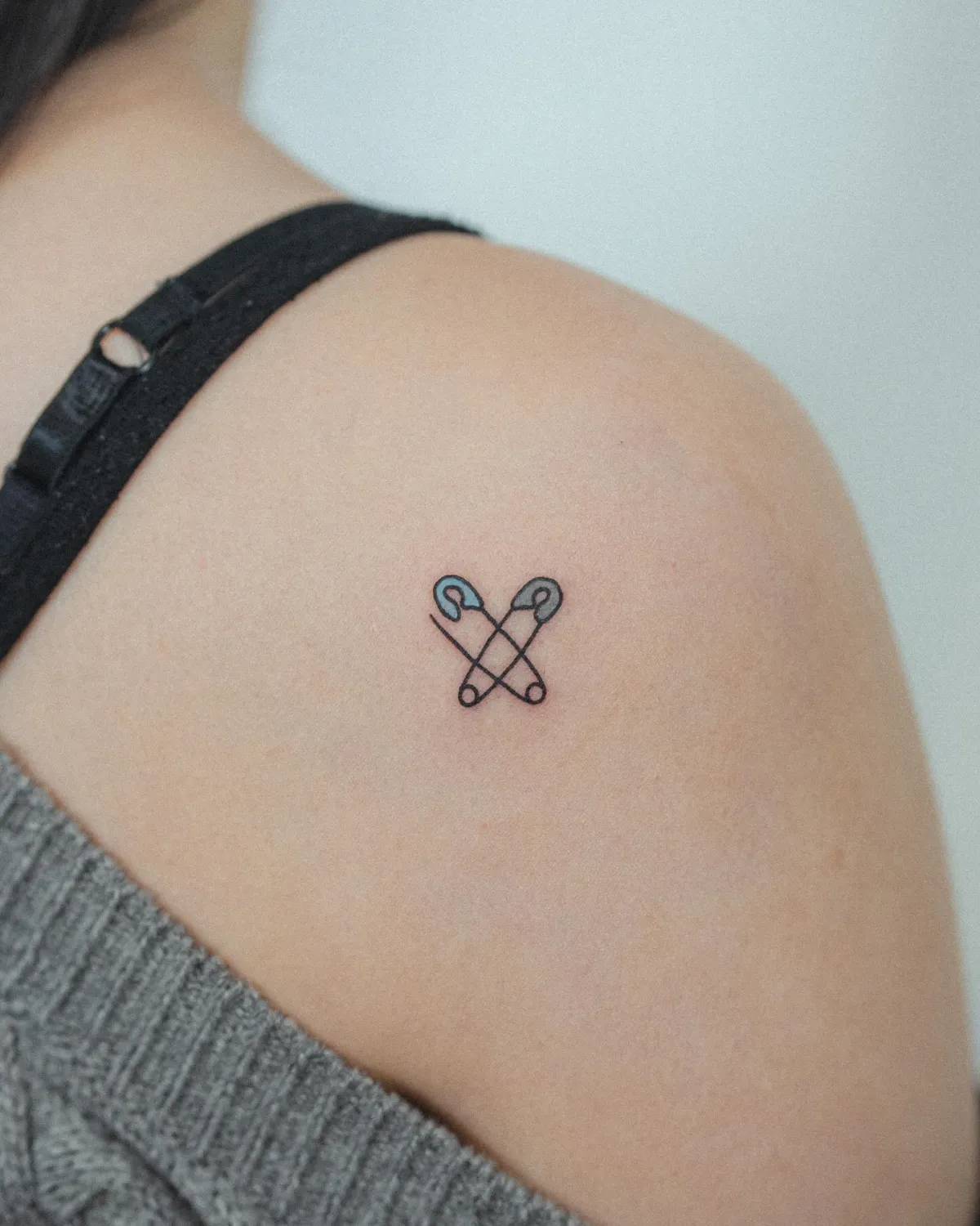kleines tattoo schulter mit sicherheitsnadel symbol