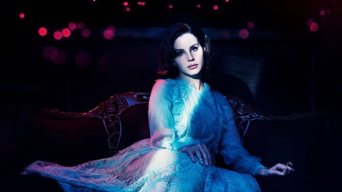 Lana Del Rey in weißem Spitzenkleid mit langen Ärmeln, schwarze Haare und Porzellanteint