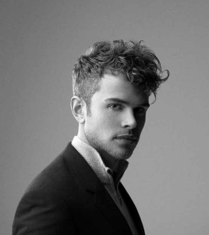 schwarz weißes foto von einem model mann, frisuren halblang gestuft locken, natürliche haare