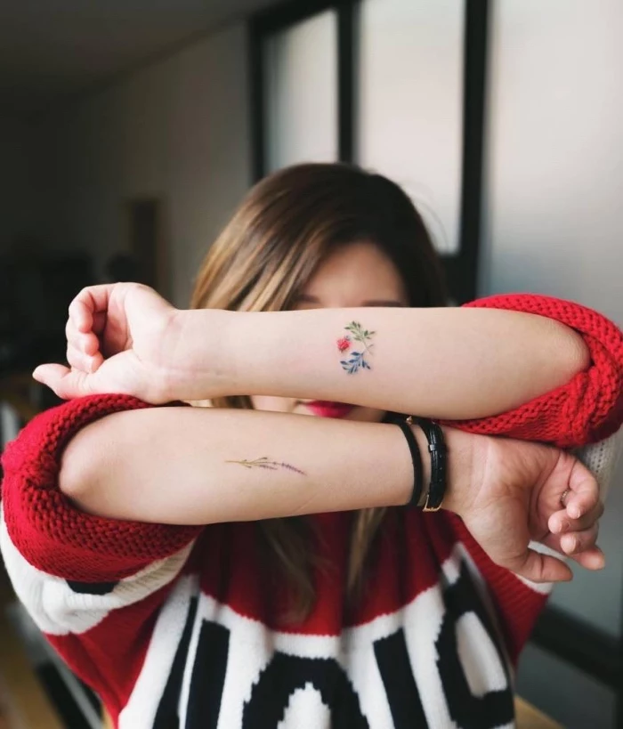 tattoo ideen für frauen, die zwei hände von einer frau werden tätowiert, roter pulli, man sieht das gesicht von der frau nicht