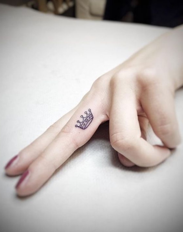 tattoo motive, eine kleine krone am inneren vom finger, mittelfinger tattoo, königliches element