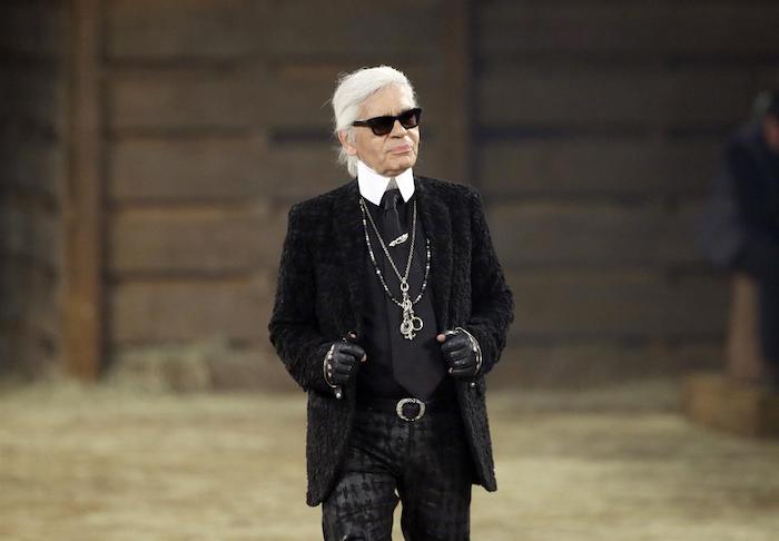 der designer karl lagerfeld mit einem schwarzen anzug und mit schwarzen sonnenbrille und langen halsketten und schwarzer sonnenbrille