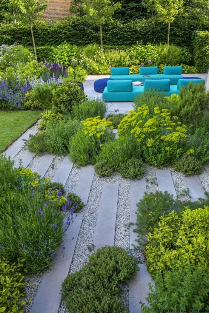 zwei blaue Sofas, ein grüner Garten mit bunten Blumen, Platten in grauer Farbe, moderne Gartengestaltung