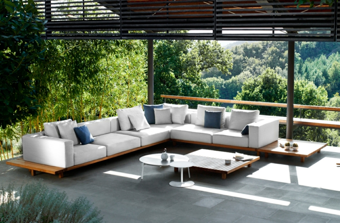 eine moderne Terrasse, Gartengestaltung Ideen, weiße Loungemöbel mit weißen und blauen Kissen, grüne Bäume