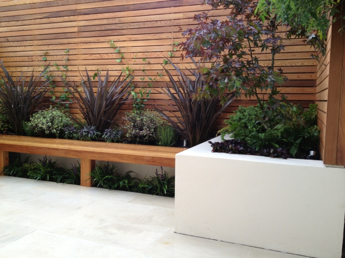ein hoher Sichtschutz, ein Hochbeet in weißer Farbe, Garten Ideen für eine moderne Gestaltung