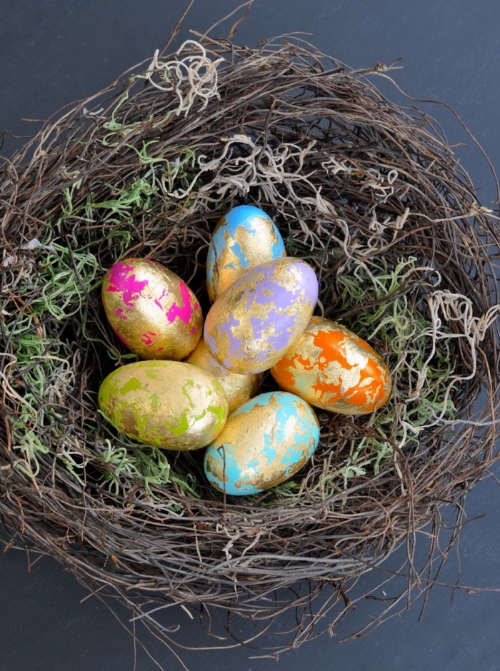 selbstgemachtes nest aus moos und dünnen zweigen, körbchen basteln, eier dekoriert mit blattgold