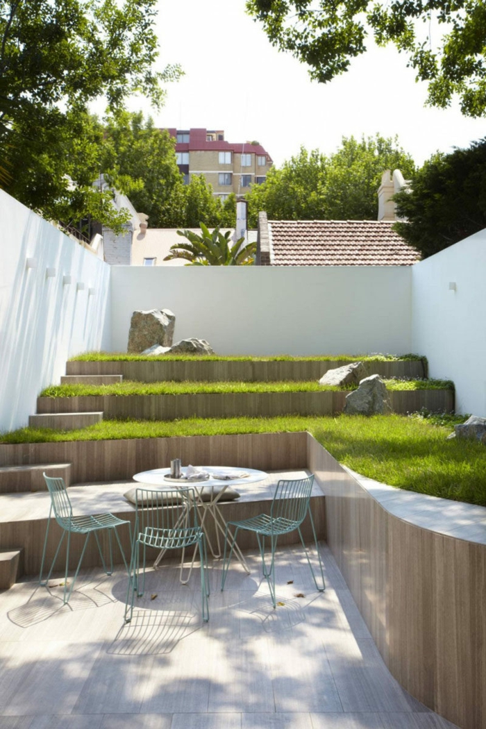 ein Garten auf Etagen mit grünem Gras, einige Gartenmöbel in blauer Farbe, Gartengestaltung Beispiele