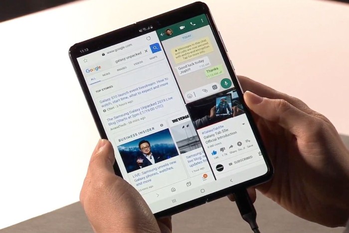 das erste faltbare Smartphone von Samsung Galaxy Fold, zwei Hände und ein schwarzes großes faltbares Smartphone mit zwei Displays