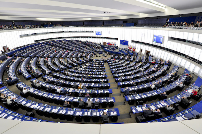 das parlament der europäischen union, viele menschen und blaue schreibtische und stähle und weiße wände
