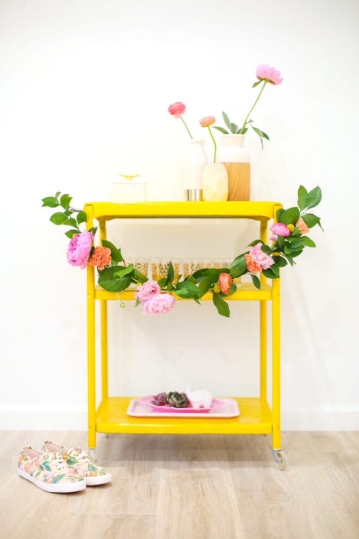 gelber tisch dekoriert mit girlande aus grünen blättern und frühlingsblumen, deko ideen selbst machen