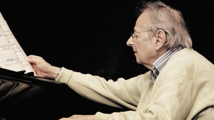 alter mann mit einer grauen armbanduhr und einer brille, ein buch und piano, der pianist André Previn 